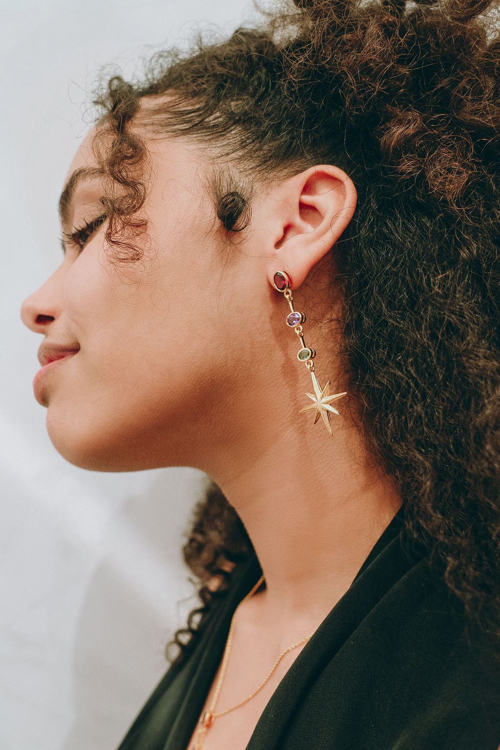 Northern Star gold vermeil earrings worn in profile, the rhodolite, amethyst and green apatite descending to an eight-pointed star beside the face